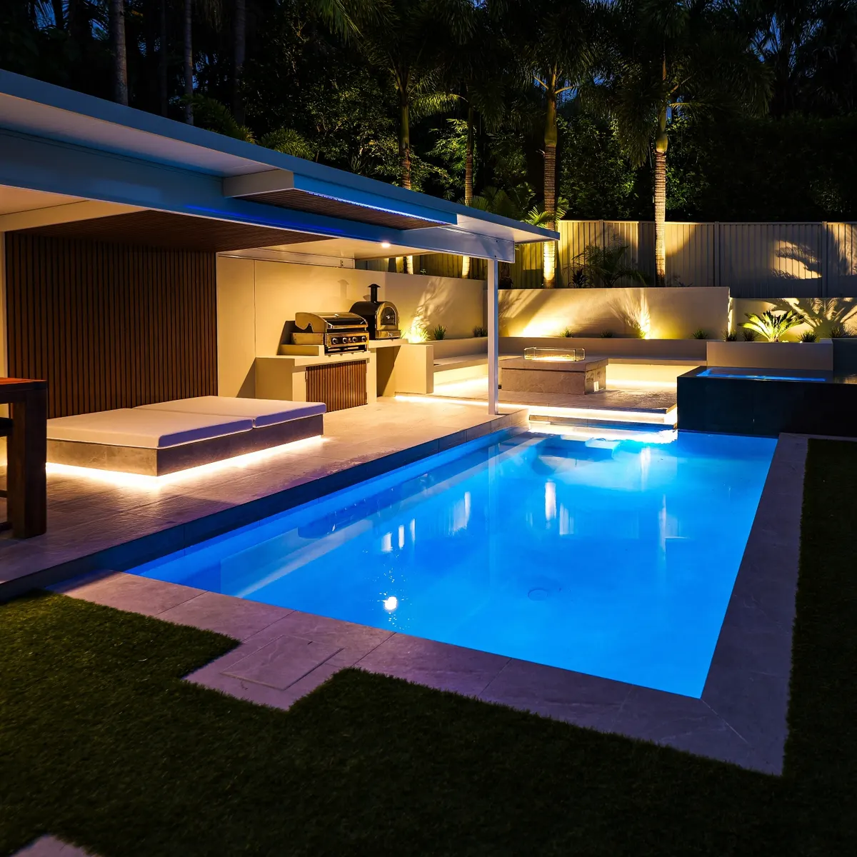 Backyard pool at dusk with LED lighting, outdoor kitchen and fire pit, Bonogin
